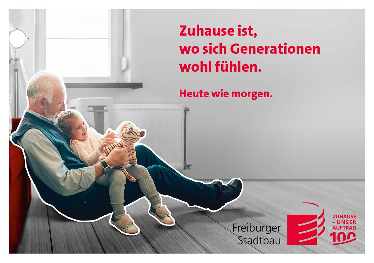 Das Foto ist eine Werbeanzeige mit Bezug auf das Wohnen heute wie morgen. Es zeigt einen Großvater mit seinem Enkel samt Teddybär auf dem Schoß. Der Slogan lautet: Zuhause ist, wo sich Generationen wohlfühlen.