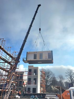 Raummodule auf Schwerlasttransportern angeliefert und auf der Baustelle montiert 